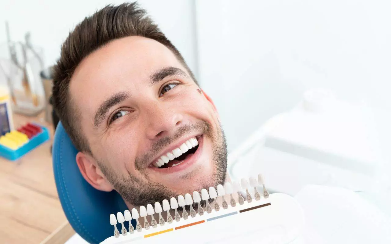 pros-and-cons-of-professional-teeth-whitening-compared-to-at-home-kits - A man smiles while undergoing professional teeth whitening at a dentists chair.