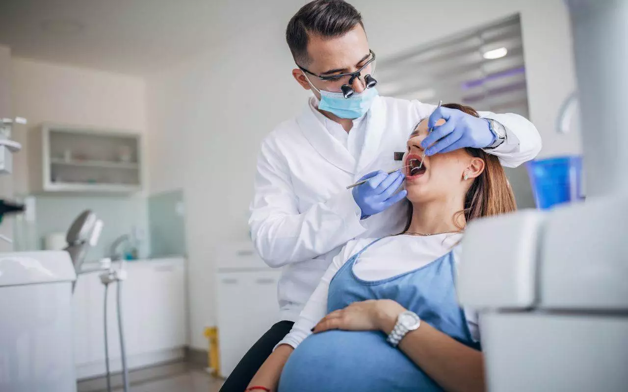 A pregnant woman is being examined by a dentist.